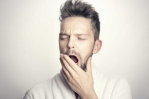 Homme qui baille avec main devant la bouche