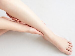 Jambe d'une femme qui tient sa jambe sur fond blanc