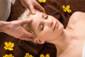 femme allongée qui se fait masser le visage pour ses aouphènes :comment les soigner?