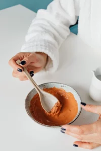 pot rempli d'argile rouge mélangée avec une cuillère
