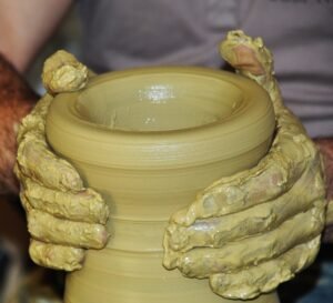 Pot d'argile jaune tenu entre 2 mains