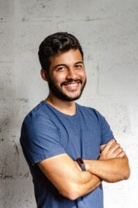 un homme souriant se tient debout avec les bras croisés, symbole d'une mentalité optimiste grâce à la pensée positive !