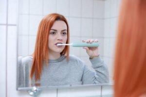 femme devant miroir qui brosse ses dents